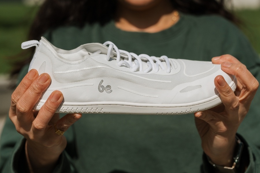Holding a women's vegan barefoot sneaker, sole in view Holding a women's vegan barefoot sneaker, sole in view